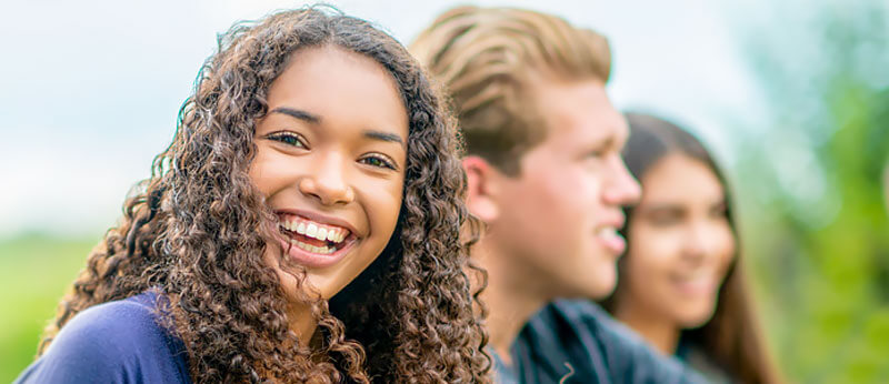 A smiling teenage girl socializes with her friends.